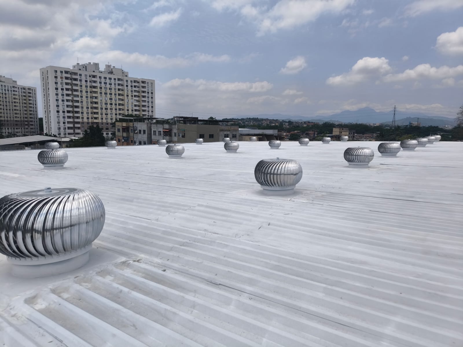 Cobertura industrial com exaustores eólicos instalados e pintura com tinta térmica
